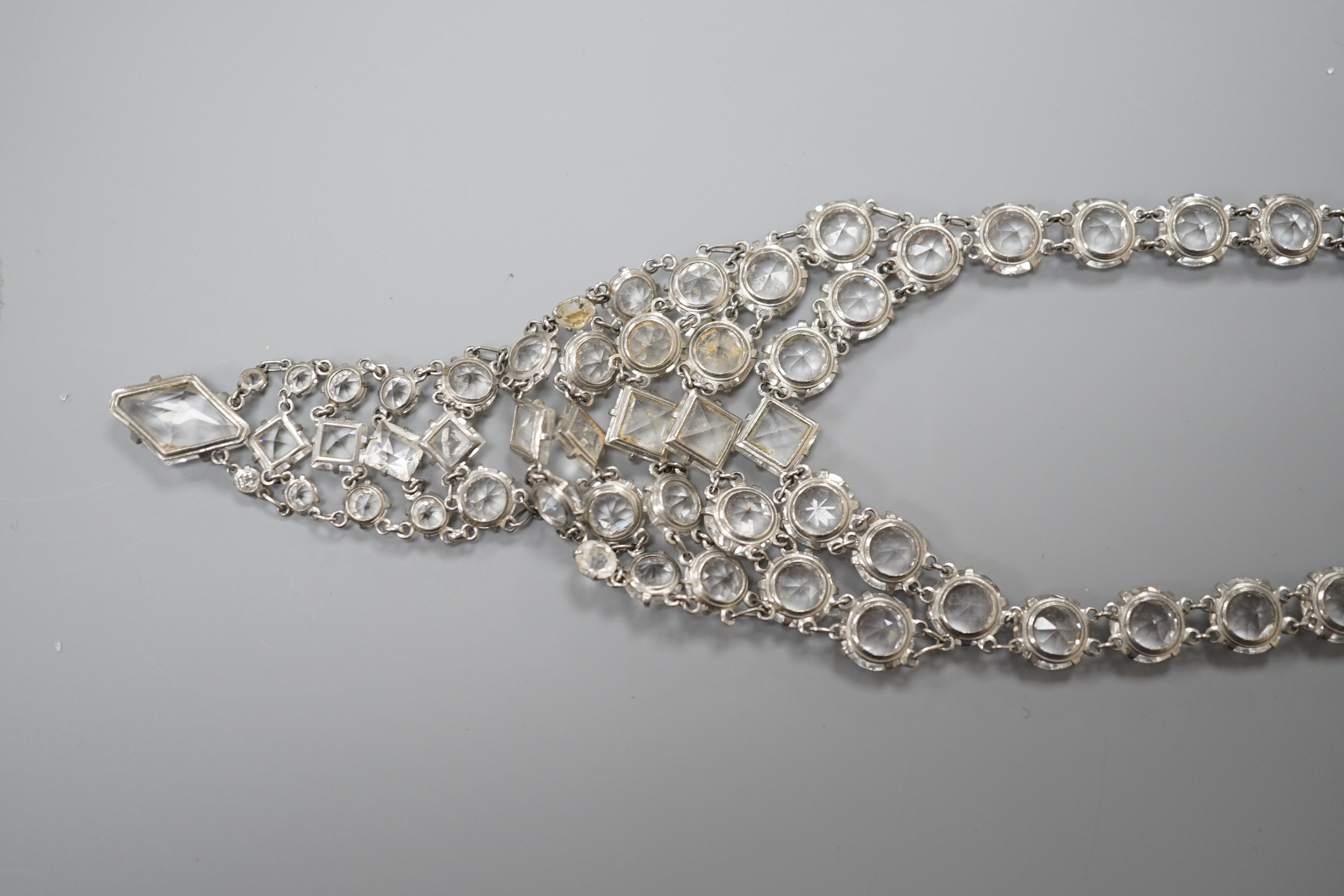 An early 20th century ornate white metal and facet cut paste set drop necklace, overall approx. 44cm.